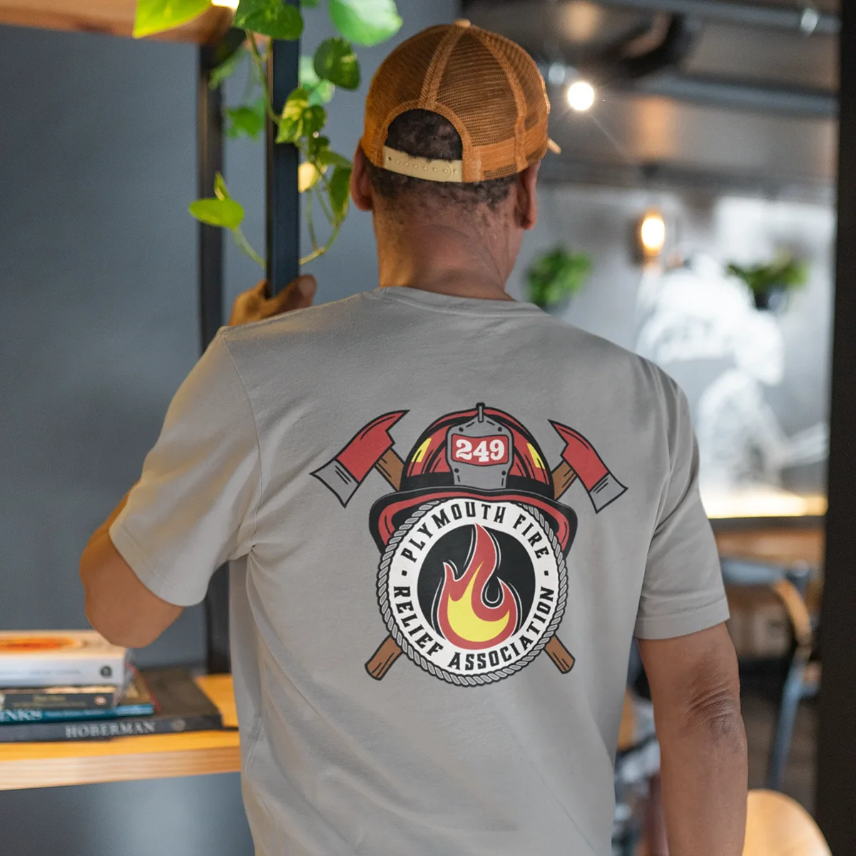 Plymouth-Fire-Relief-Association-Tee A man wearing a gray T-shirt with the Plymouth Firefighters Relief Association logo on the back.